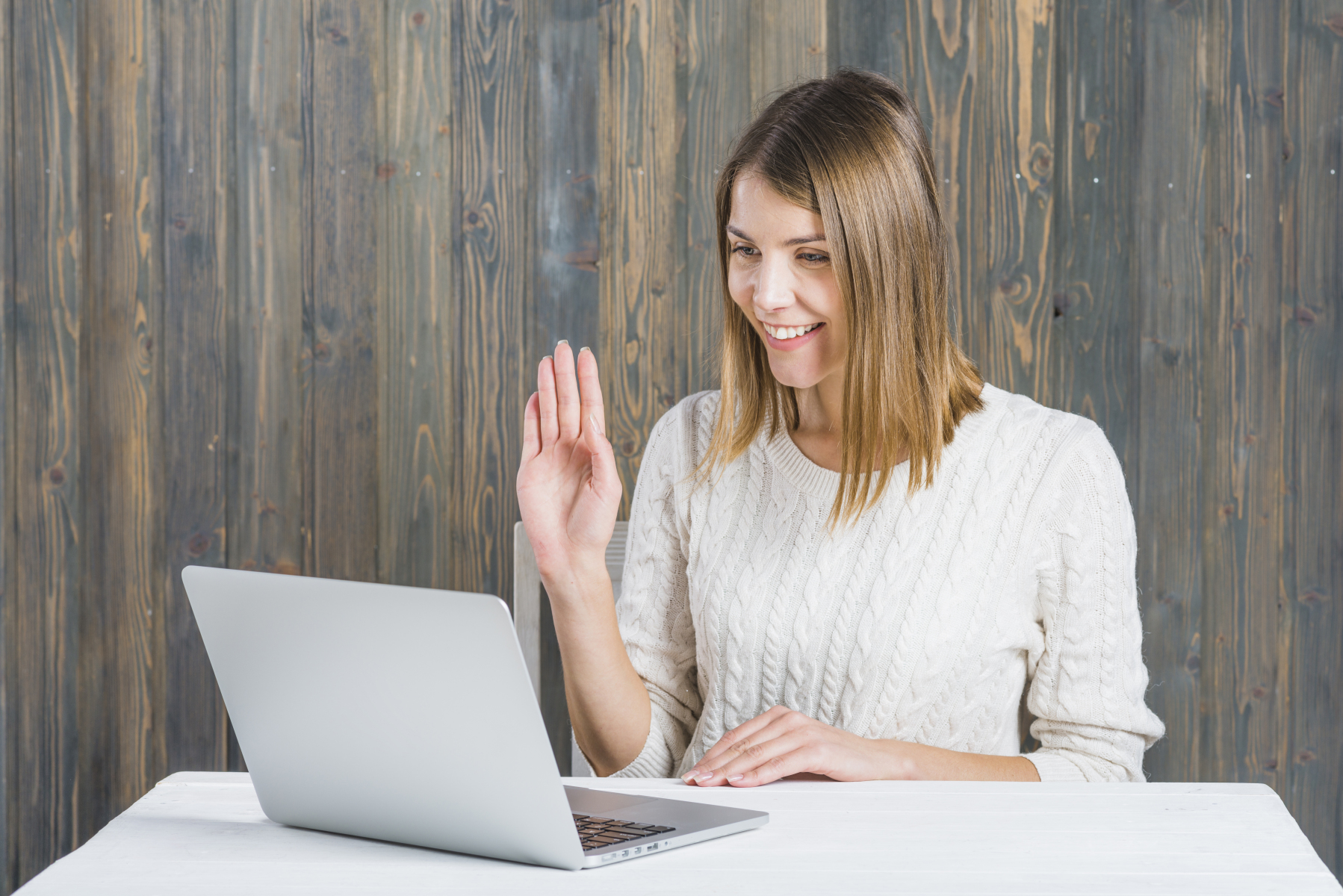 happy-woman-waving-her-hand-while-using-laptop-desk